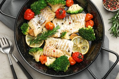 Photo of Tasty cod cooked with vegetables served on grey table, flat lay