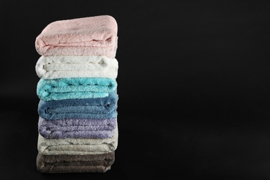 Photo of Different fresh soft terry towels on dark background. Space for text