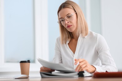 Photo of Woman working with documents at wooden table in office