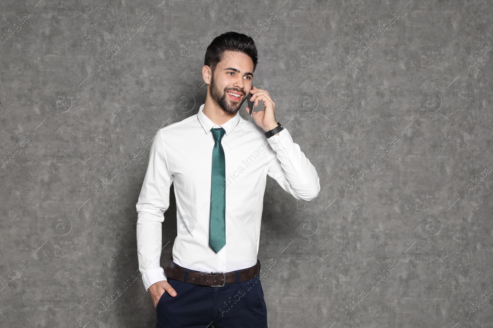 Photo of Portrait of businessman talking on phone against grey background