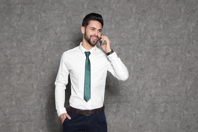 Portrait of businessman talking on phone against grey background