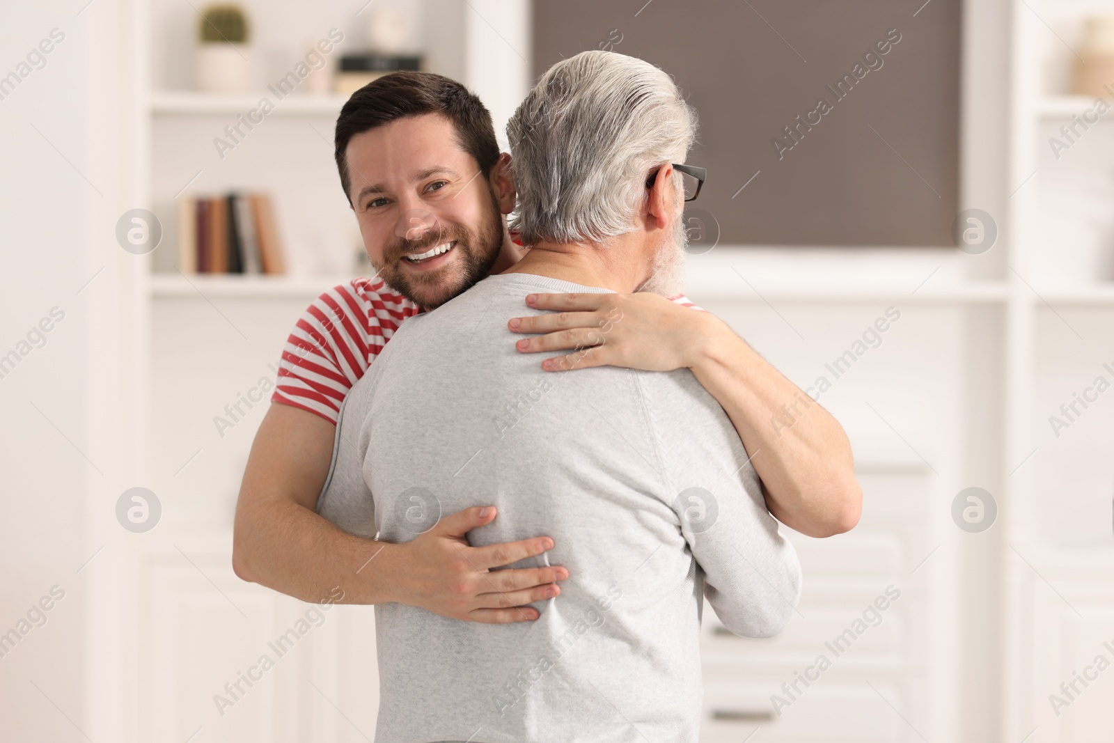 Photo of Happy son and his dad hugging at home