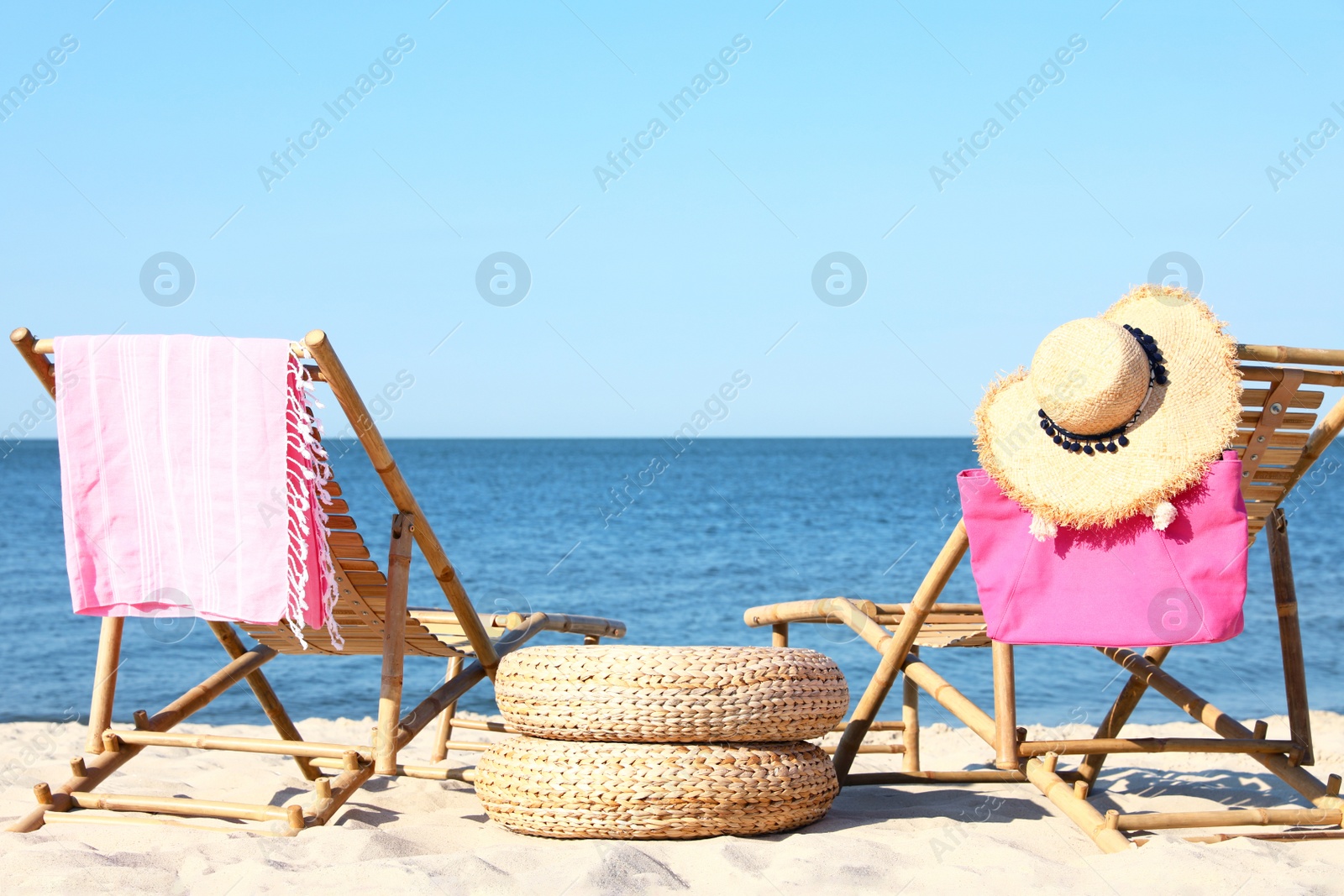 Photo of Empty wooden sunbeds and beach accessories on sandy shore