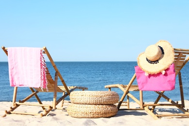 Empty wooden sunbeds and beach accessories on sandy shore