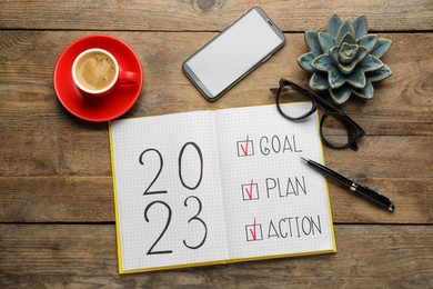 Photo of Flat lay composition of notebook with text 2023 Goal, Plan, Action on wooden table. New year resolutions