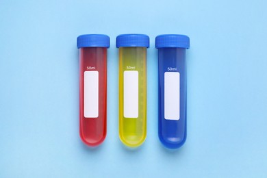 Photo of Test tubes with colorful liquids on light blue background, flat lay. Kids chemical experiment set