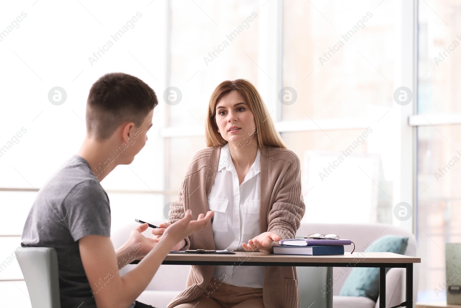 Photo of Young female psychologist working with teenage boy in office