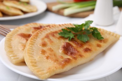 Photo of Delicious fried cheburek with cheese and parsley on white tiled table