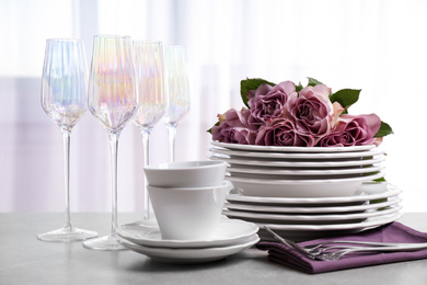 Set of glasses and dishes with flowers on light grey table