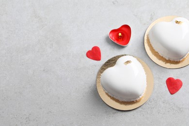 Photo of St. Valentine's Day. Delicious heart shaped cakes, candle and confetti on light grey table, flat lay. Space for text