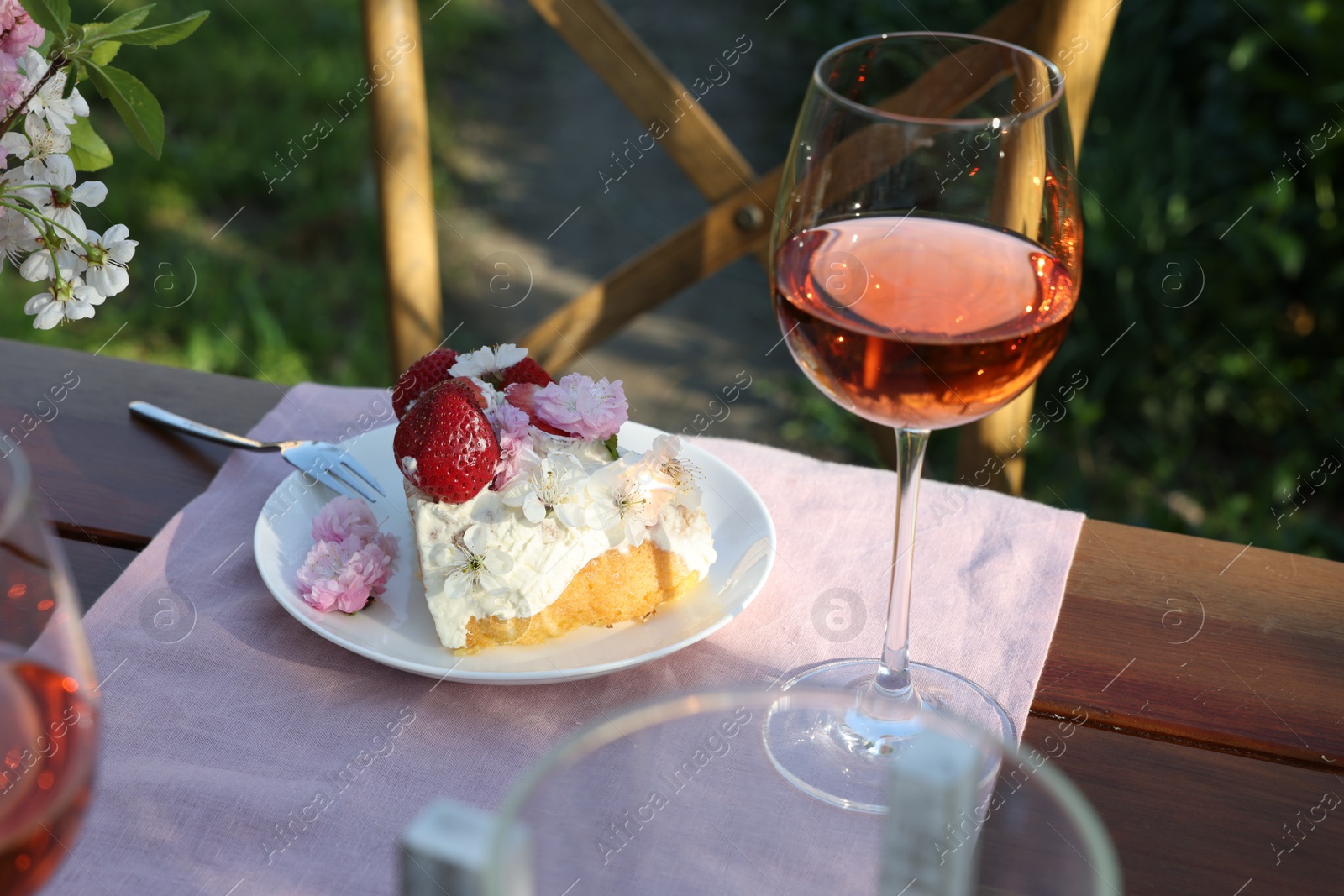 Photo of Glass of wine and cake on table served for romantic date in garden