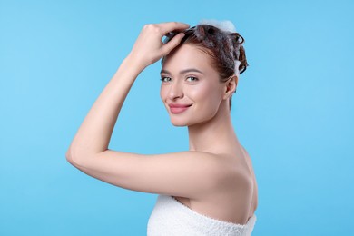 Photo of Happy young woman washing her hair with shampoo on light blue background