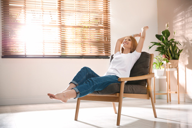 Photo of Young woman relaxing in armchair near window at home. Space for text