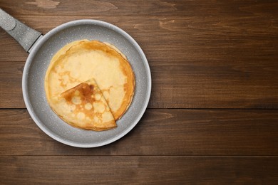 Photo of Frying pan with delicious crepes on wooden table, top view. Space for text