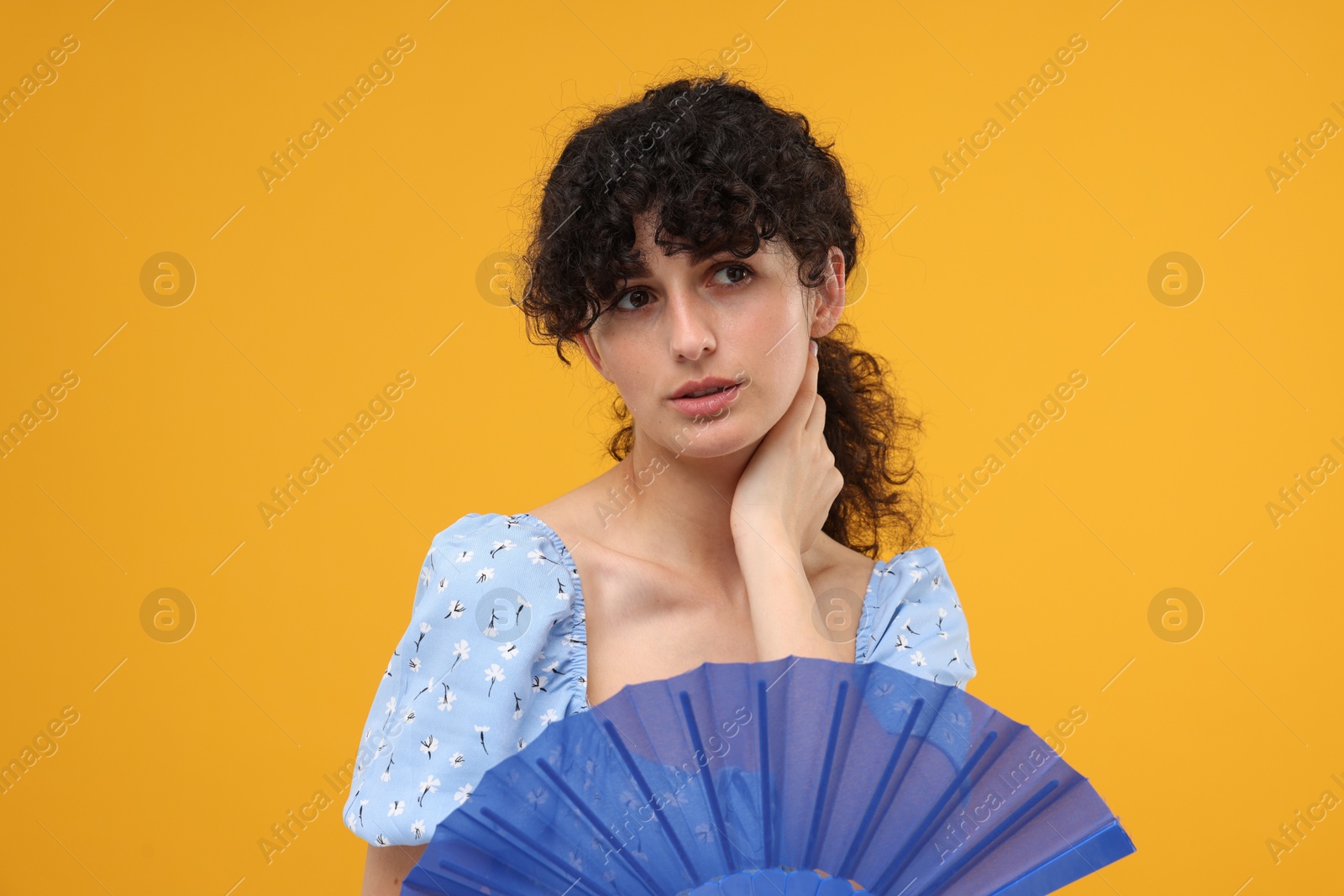 Photo of Woman with hand fan suffering from heat on orange background