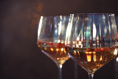 Elegant glasses with white wine on brown background, closeup