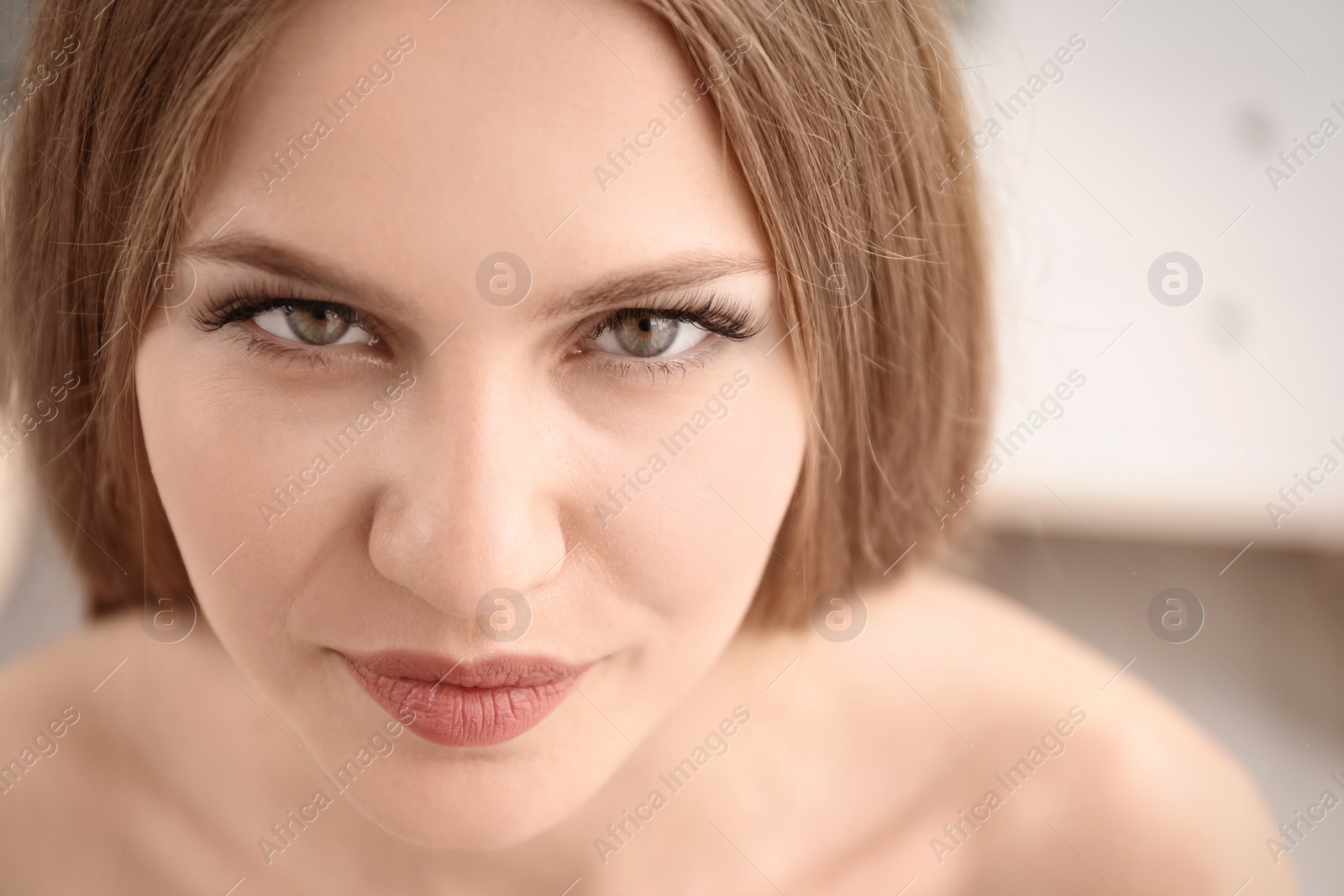 Photo of Attractive young woman with beautiful eyelashes on blurred background