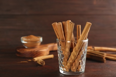 Aromatic cinnamon sticks in glass on wooden table, space for text