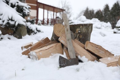 Axe, chopped wood and wooden log outdoors on winter day