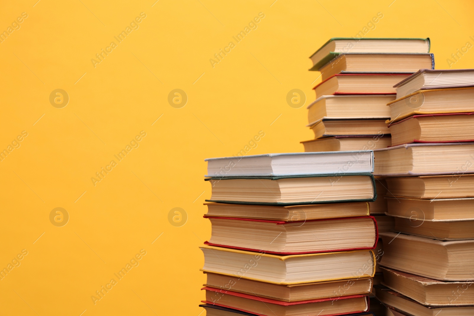 Photo of Many hardcover books on orange background, space for text. Library material