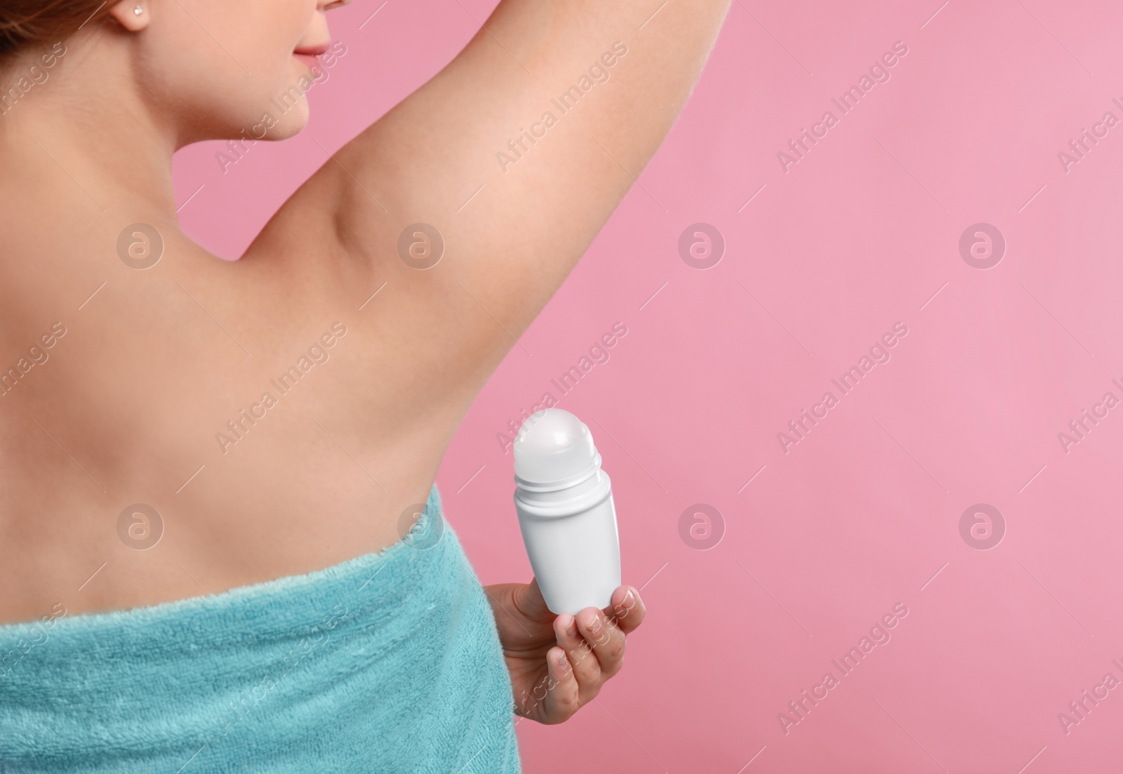 Photo of Young woman applying deodorant to armpit on pink background, closeup. Space for text