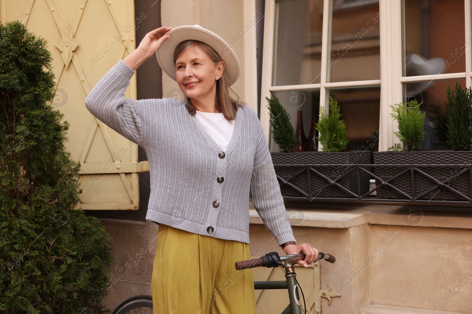 Photo of Beautiful senior woman standing near bicycle outdoors, space for text