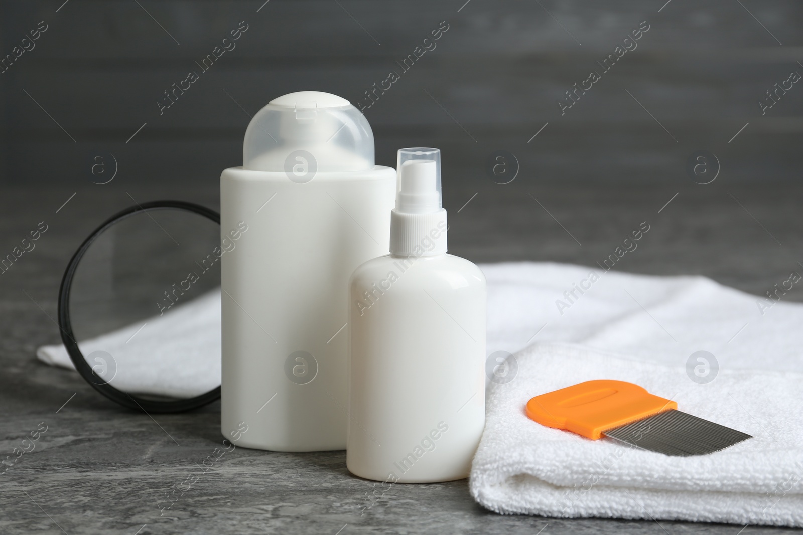 Photo of Cosmetic products, lice comb, magnifying glass and towel on grey table