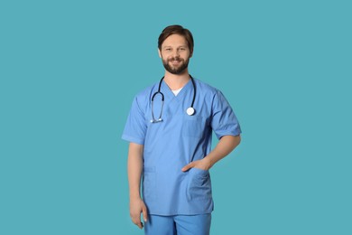 Happy doctor or medical assistant (male nurse) with stethoscope on turquoise background