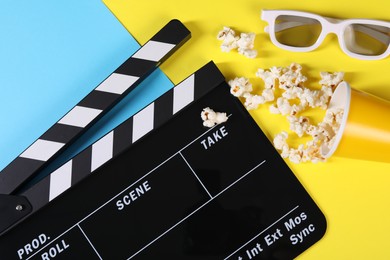 Photo of Clapperboard, popcorn and 3D glasses on color background, flat lay