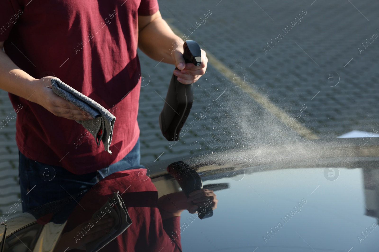 Photo of Man cleaning car hood outdoors, closeup view