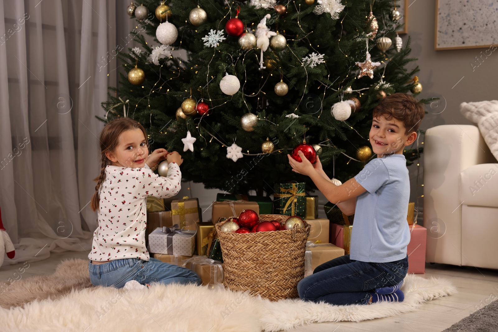 Photo of Cute little children decorating Christmas tree at home
