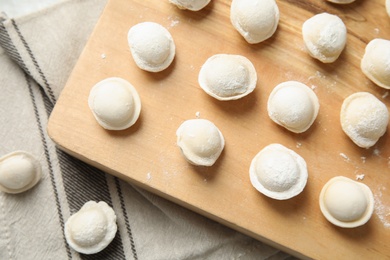 Photo of Board with raw dumplings on table, top view. Process of cooking