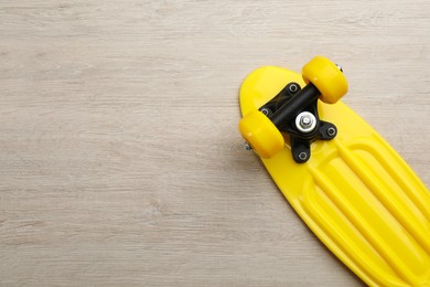 Photo of Yellow skateboard on wooden background, top view. Space for text