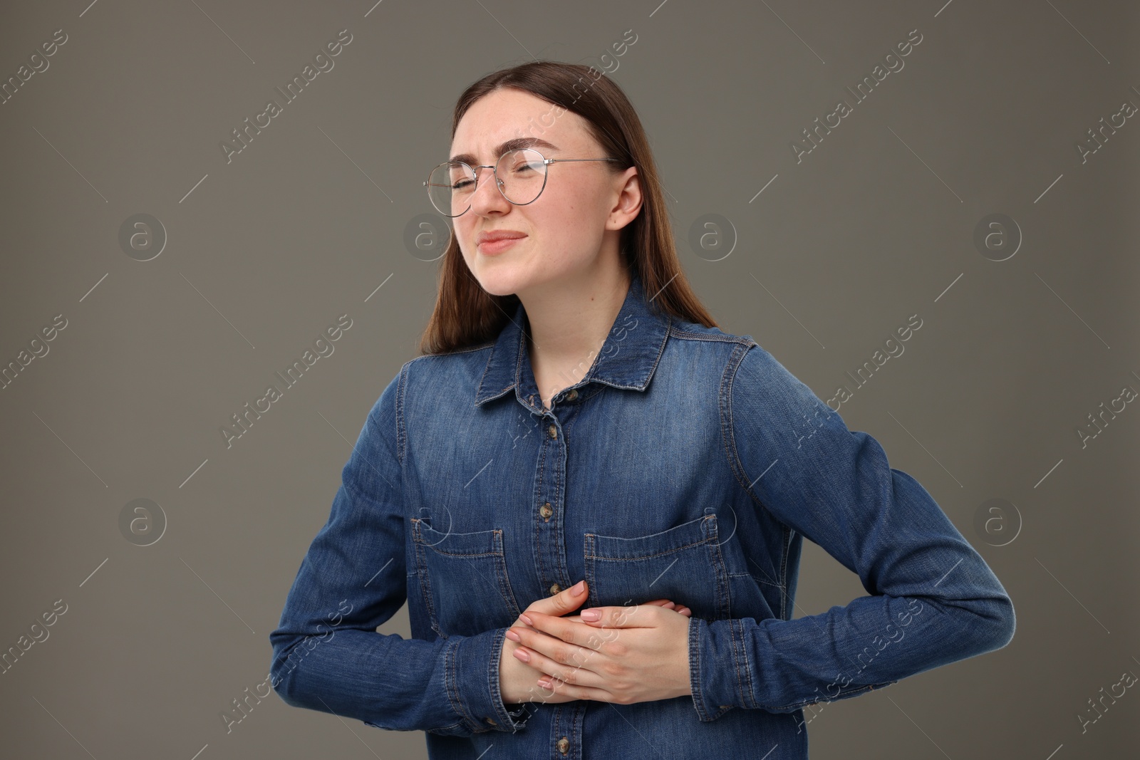 Photo of Woman suffering from stomach pain on grey background