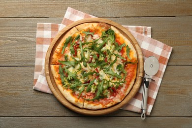 Photo of Board with delicious vegetarian pizza on wooden table, top view