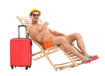 Photo of Young man with suitcase on sun lounger against white background. Beach accessories