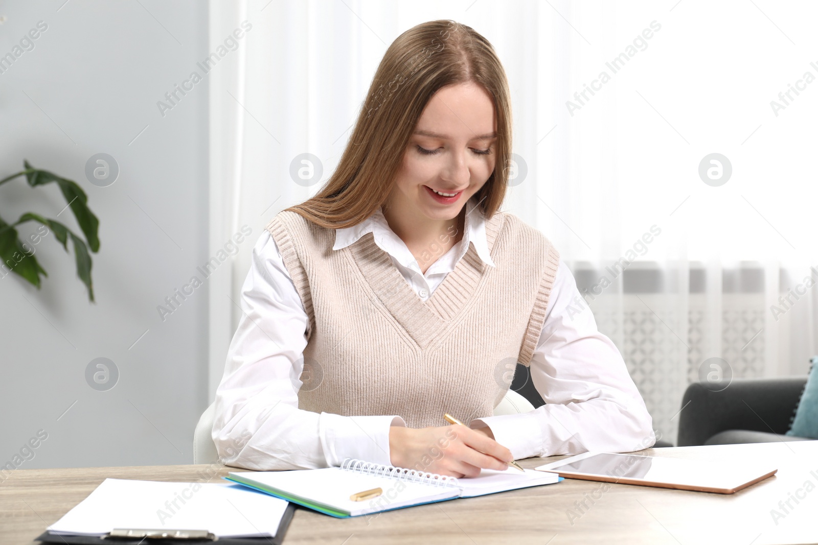 Photo of Woman taking notes at wooden table in office