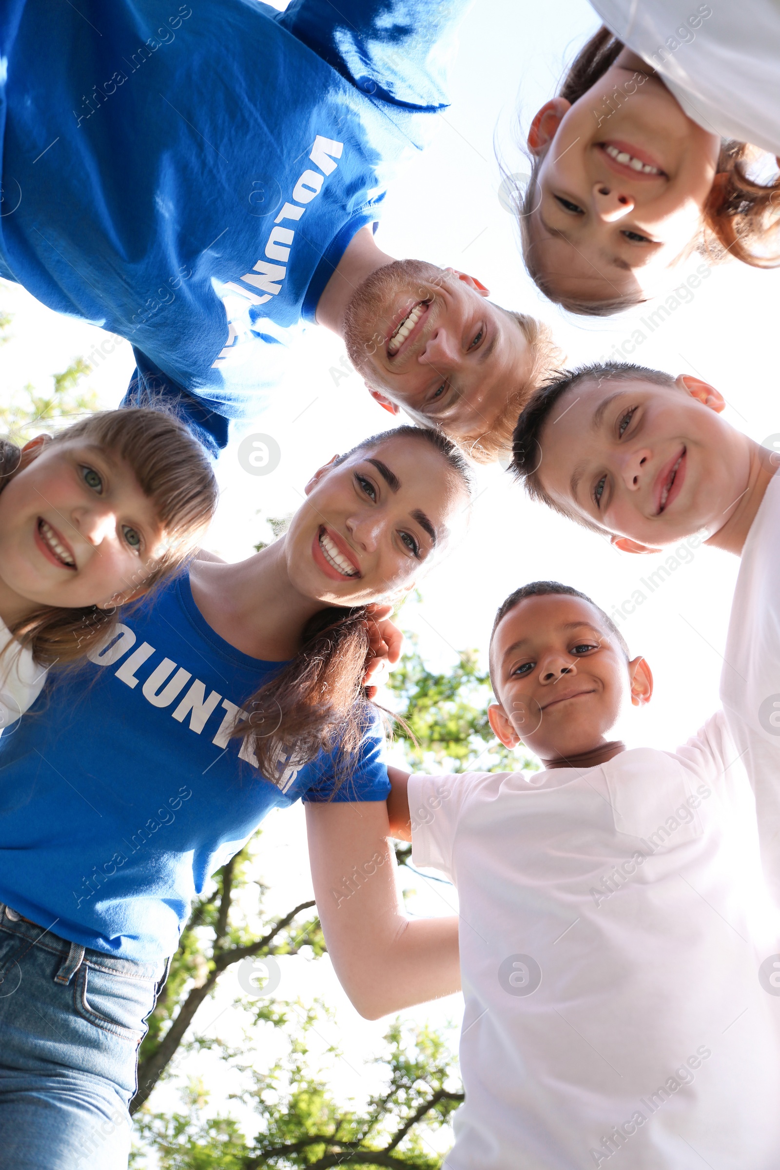 Photo of Low angle view of volunteers huddling with kids in park