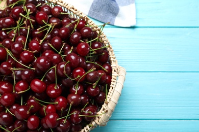 Photo of Sweet juicy cherries on light blue wooden table, top view. Space for text
