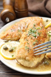 Photo of Delicious chicken piccata on wooden table, closeup