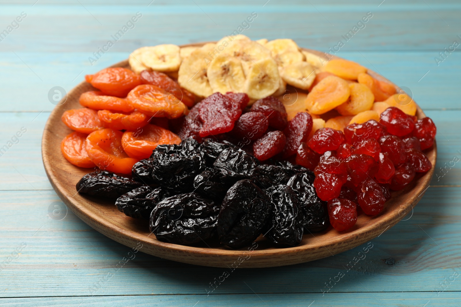 Photo of Delicious dried fruits on light blue wooden table