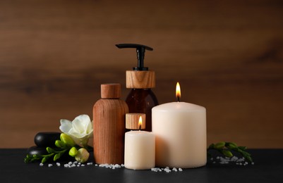 Photo of Beautiful spa composition with different care products and burning candles on black table