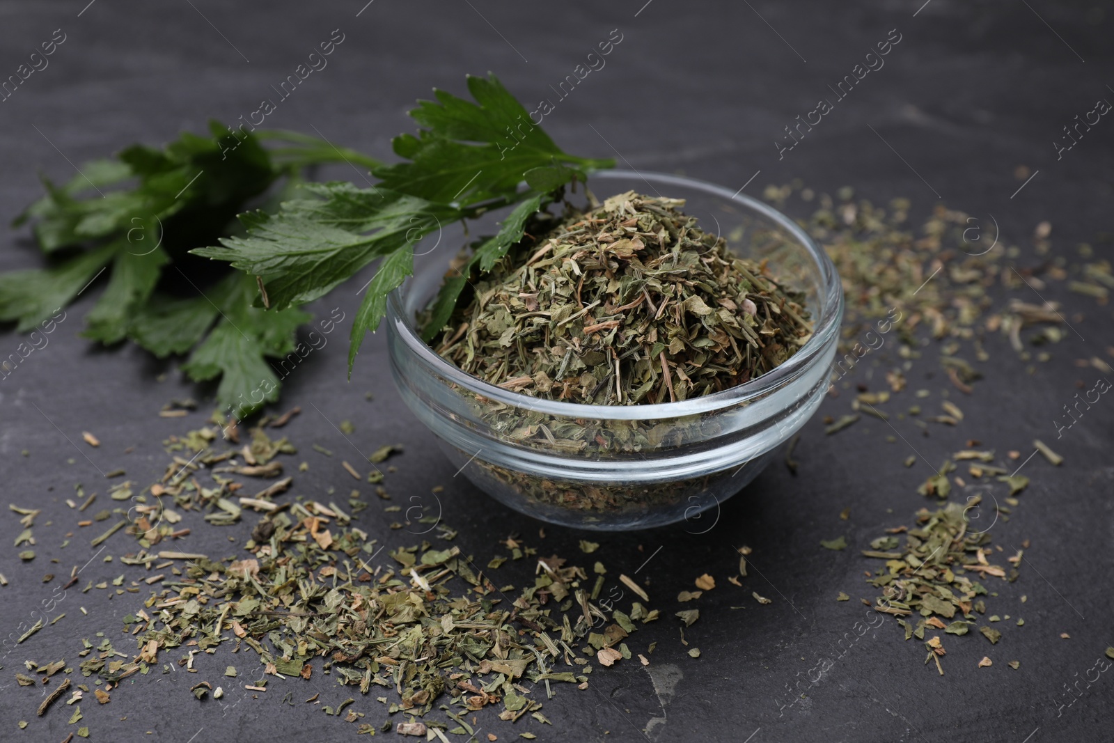 Photo of Dried parsley and fresh leaves on black table, closeup