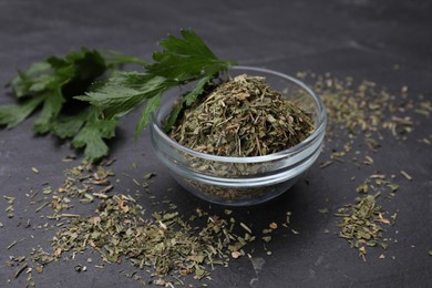 Dried parsley and fresh leaves on black table, closeup