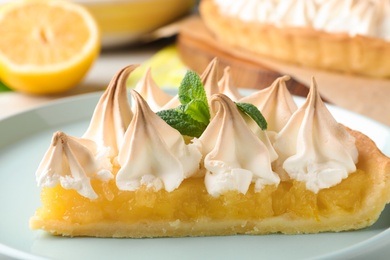 Photo of Piece of delicious lemon meringue pie with mint on plate, closeup