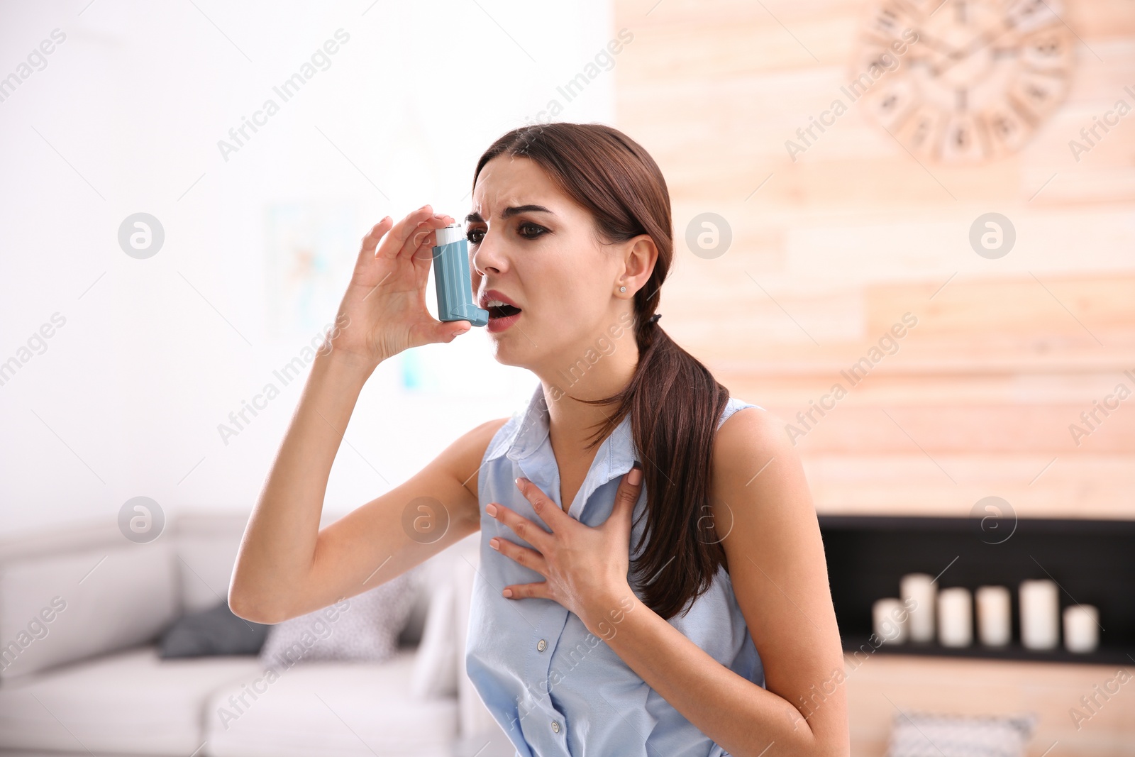 Photo of Young woman with asthma inhaler in light room