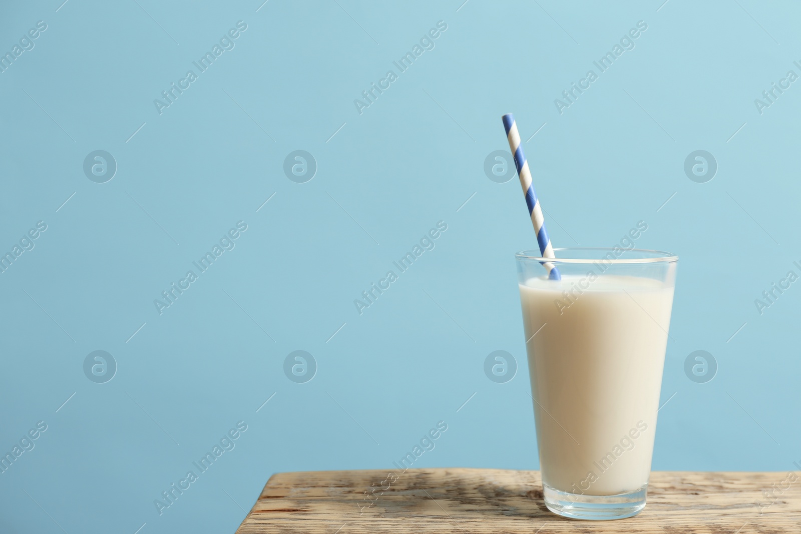 Photo of Glass of milk on table against color wall