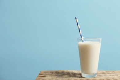 Photo of Glass of milk on table against color wall