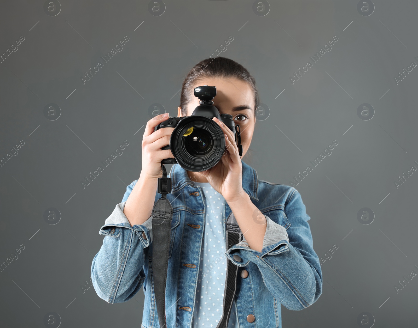 Photo of Young woman with camera against gray background. Professional photo studio