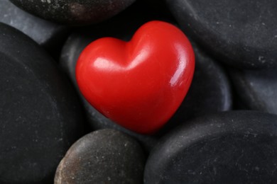 Photo of Red decorative heart on pebble stones, above view